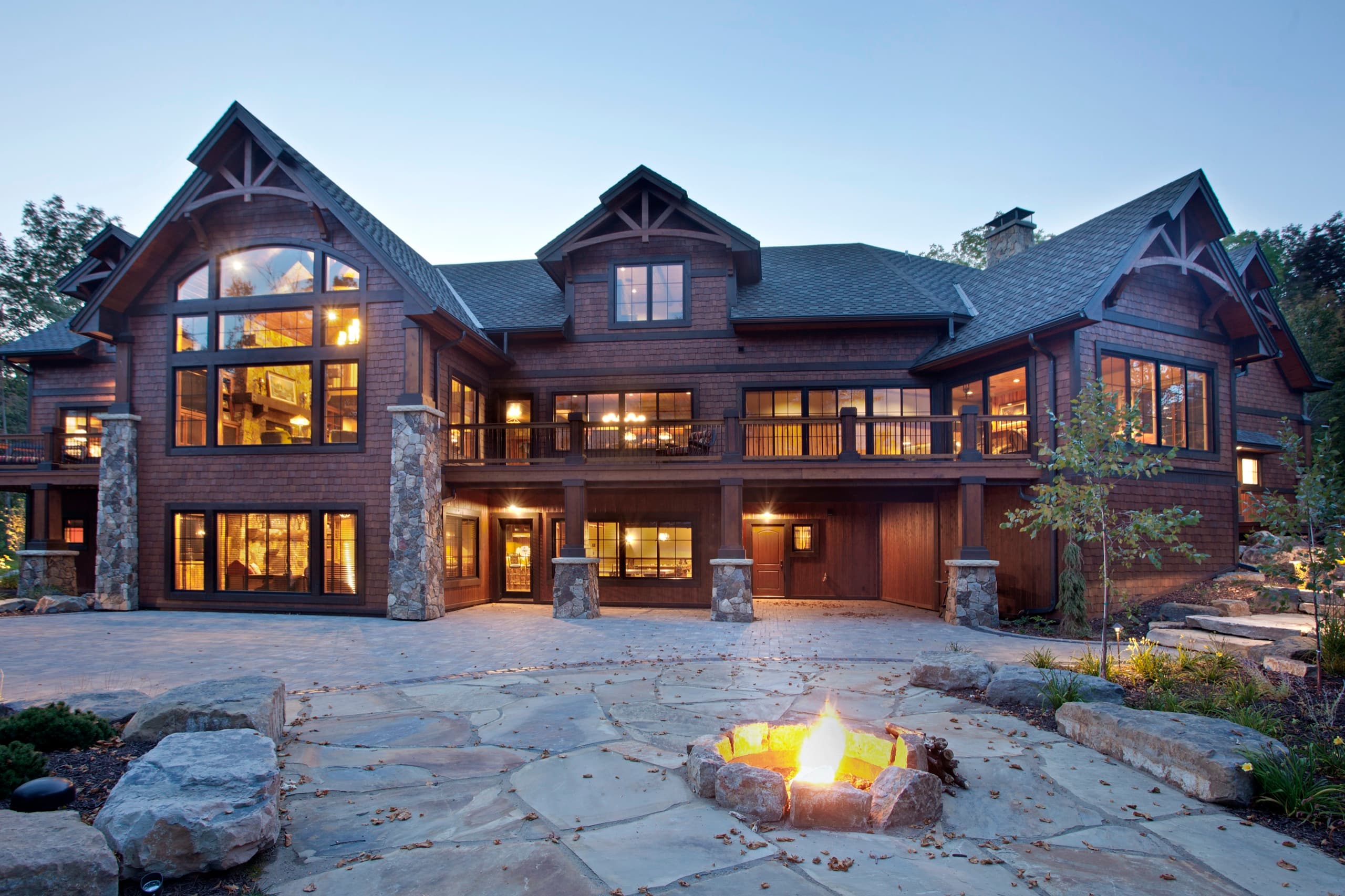 Luxury lakeside home with flagstone patio and fire pit at dusk
