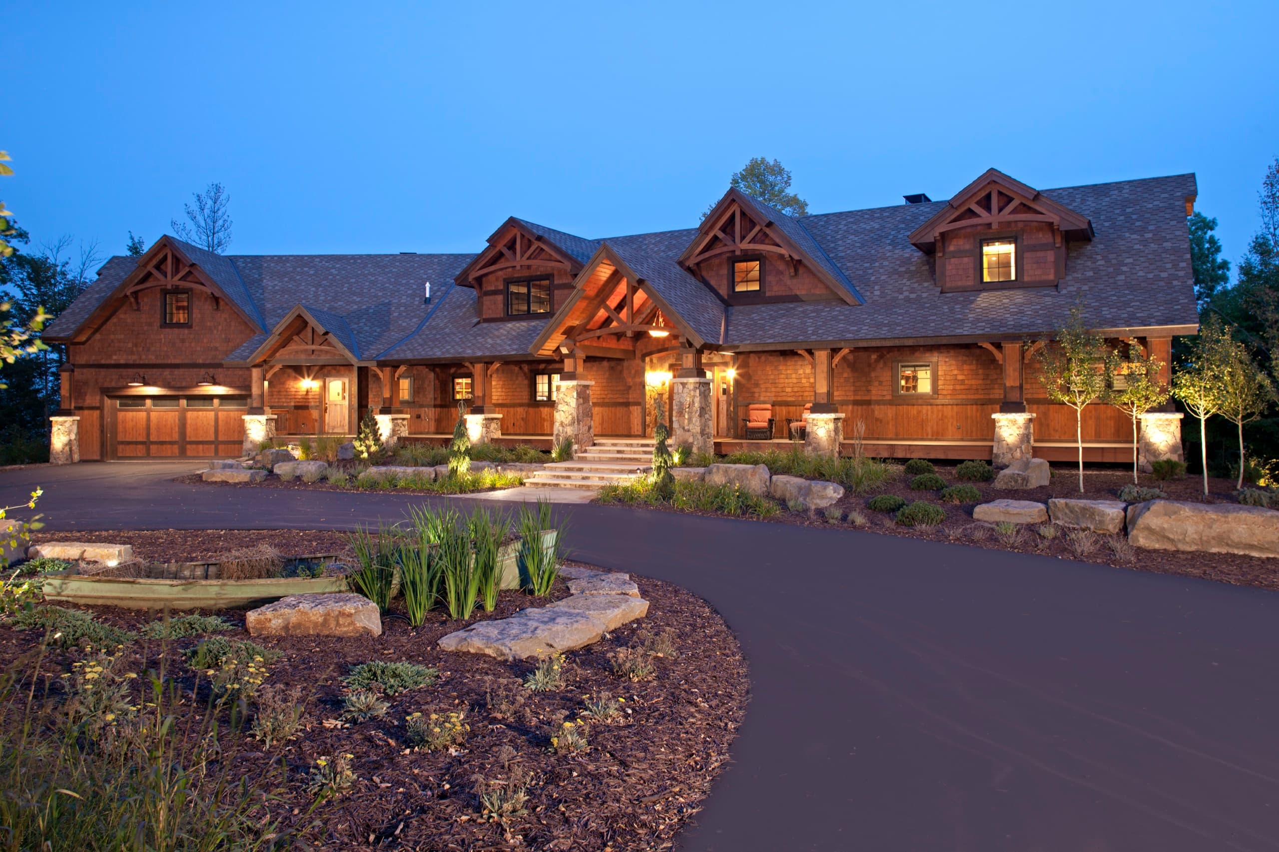 Custom craftsman home with landscape lighting and stone entry