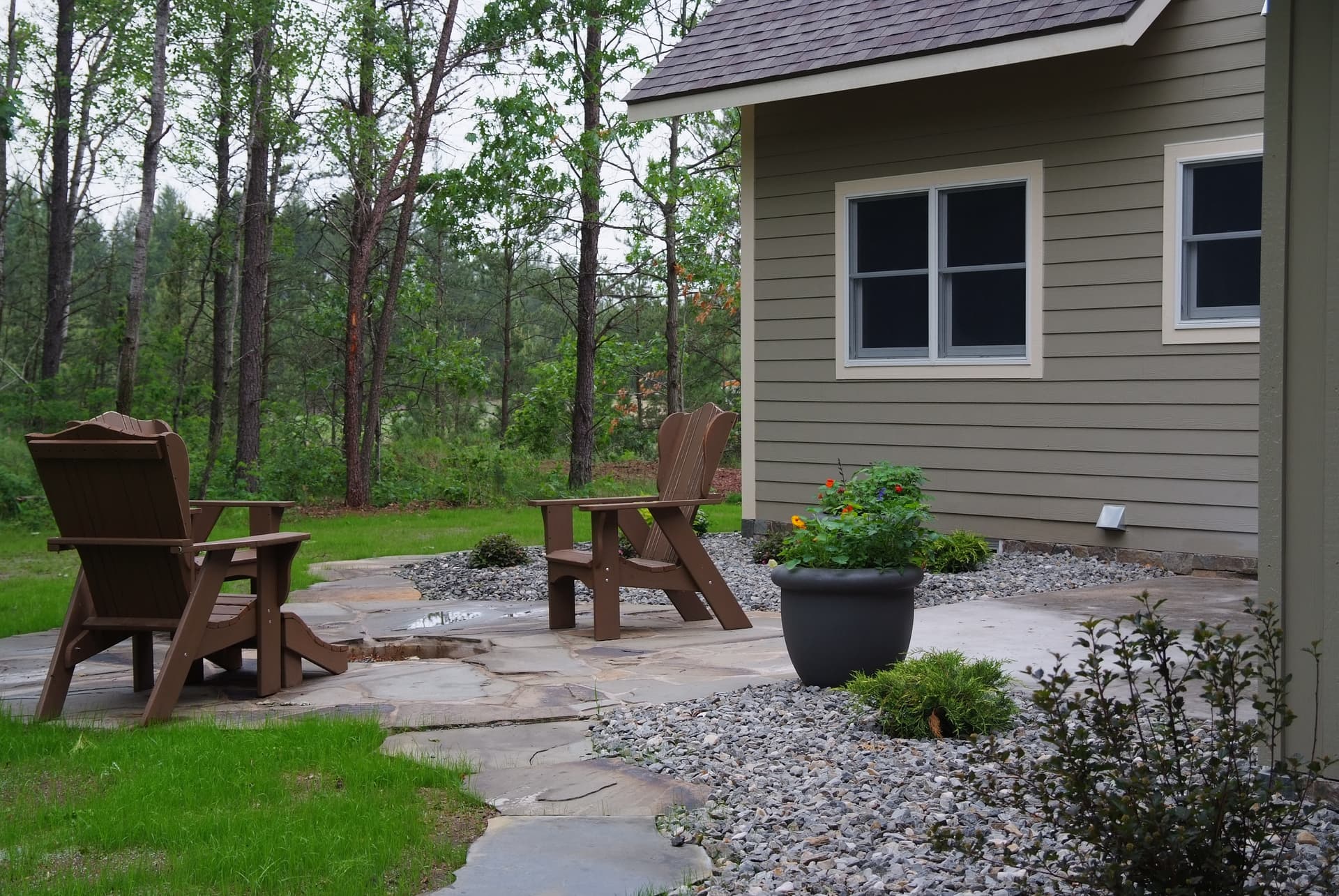 Flagstone patio with Adirondack chairs and fire pit bordering woodland
