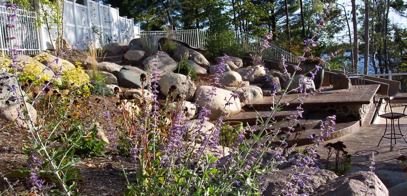 Natural boulder retaining wall with stone steps on lakeside property