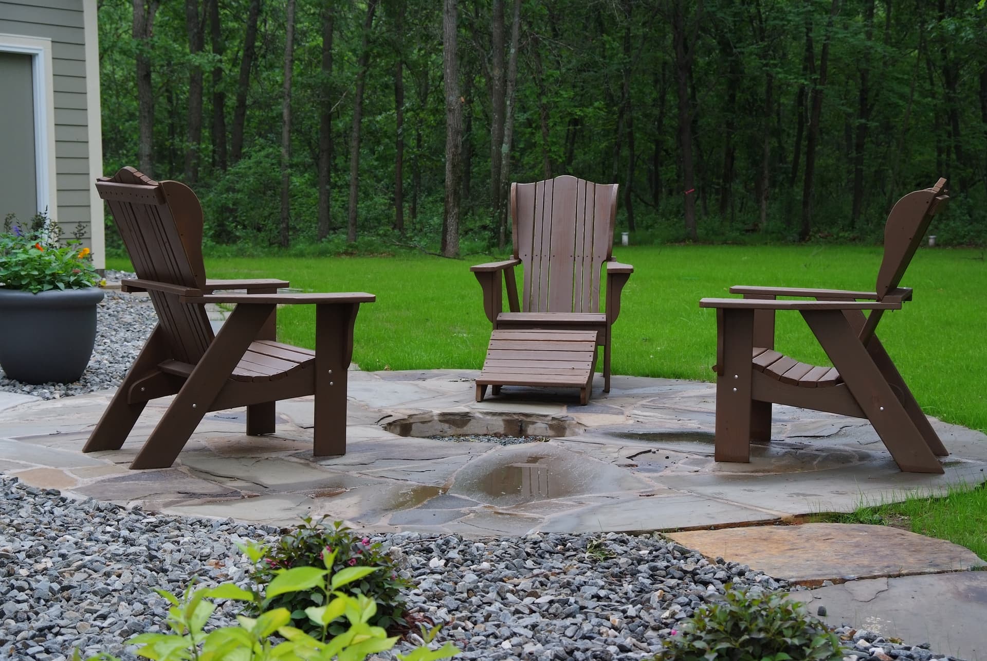 Circular flagstone fire pit with Adirondack chairs on manicured lawn