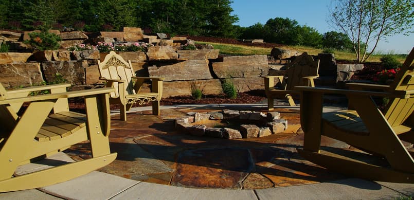 Stamped concrete patio with fire pit and natural boulder retaining wall
