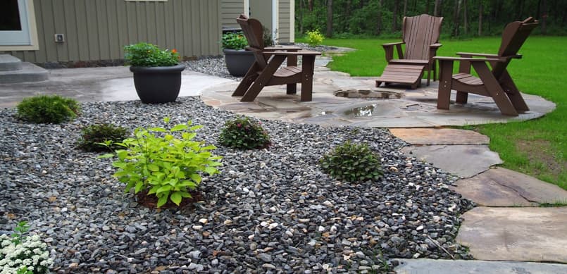 Flagstone patio with decorative gravel beds and Adirondack seating