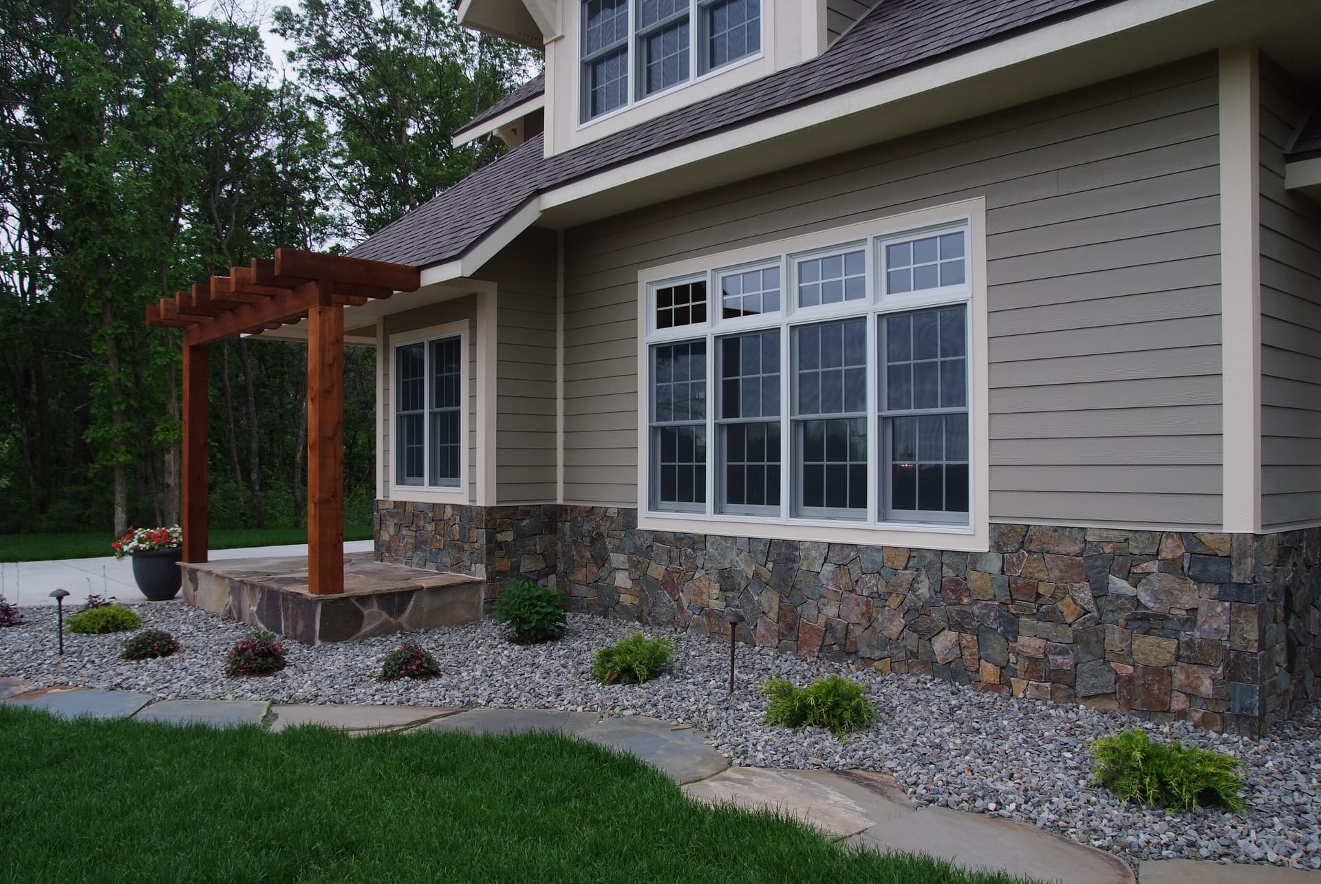 Stone-base home with timber pergola and river rock plantings