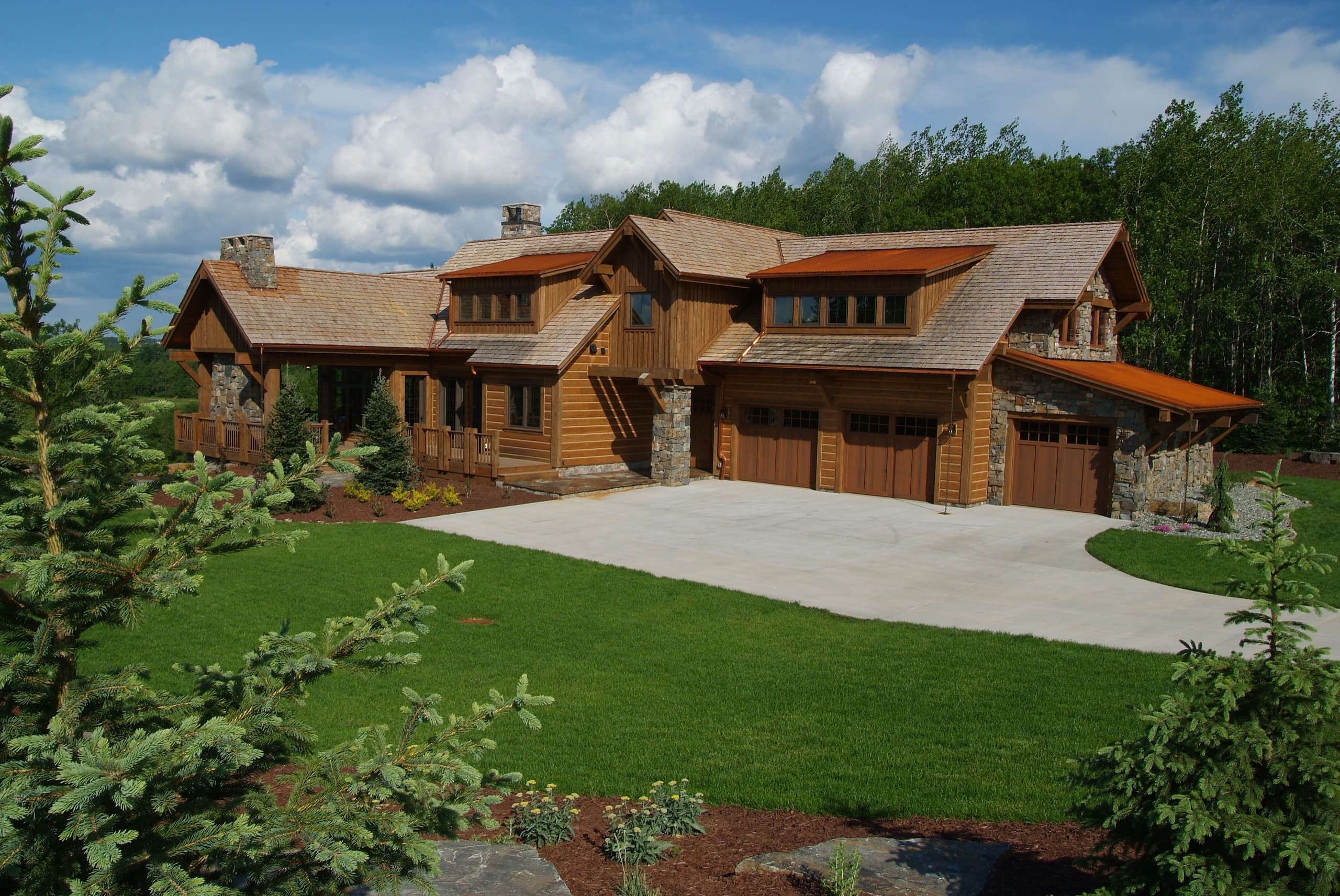Timber frame home with cedar accents and manicured driveway landscape